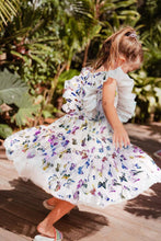 Load image into Gallery viewer, A young girl wearing a white dress with a floral pattern of butterflies in various colors, spinning around in an outdoor setting by Lola and the Boys.