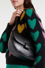 Load image into Gallery viewer, Person wearing a black sweater with colorful heart patterns, holding a black leather bag.