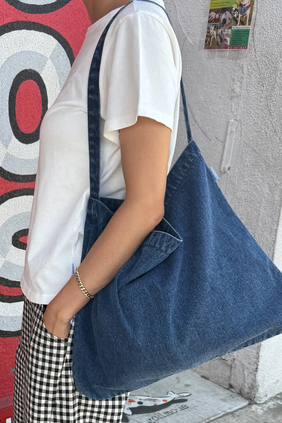 Person wearing a large blue denim bag by Le Bon Shoppe