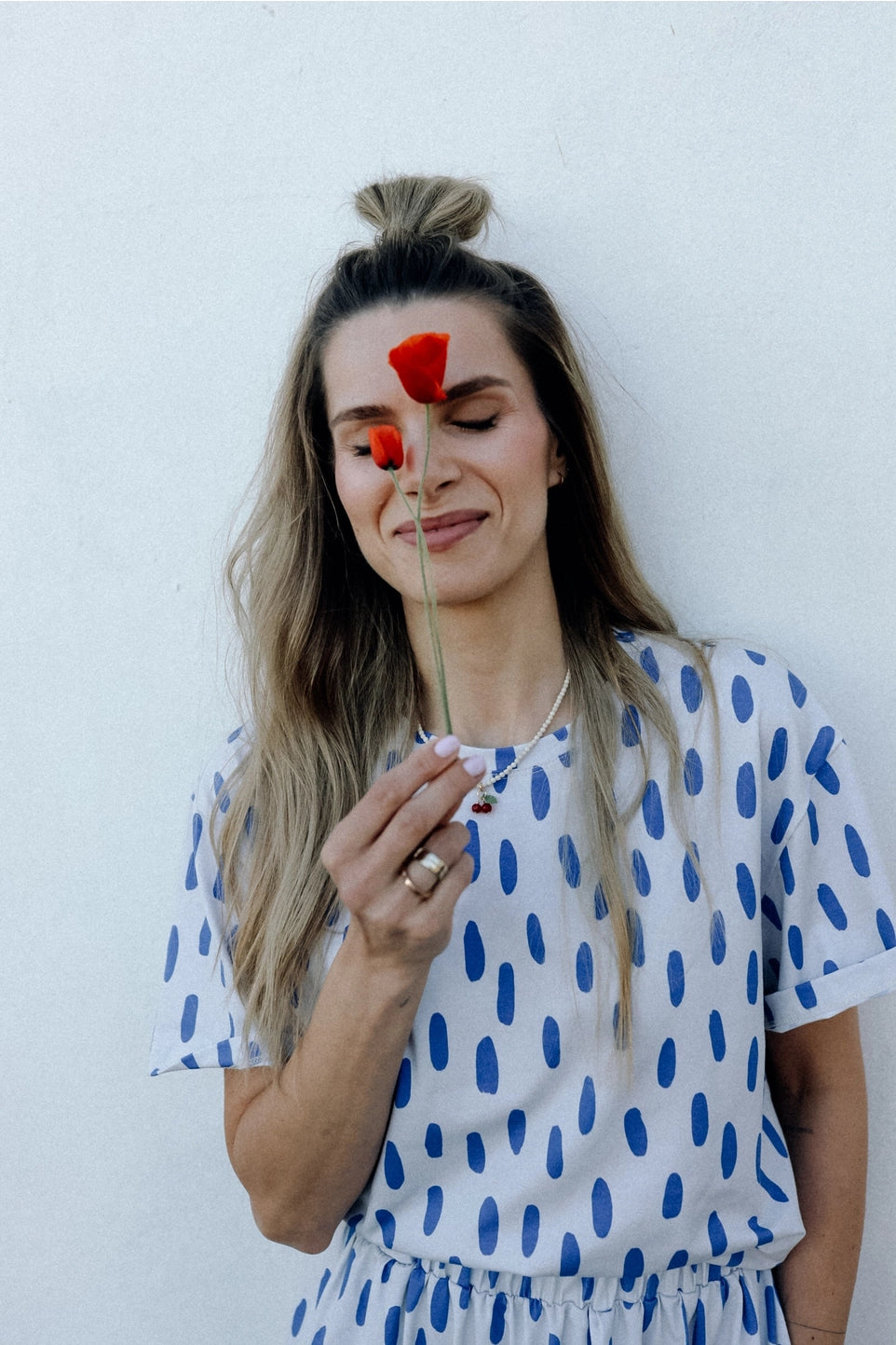 Woman holding a red flower against her face with a white background