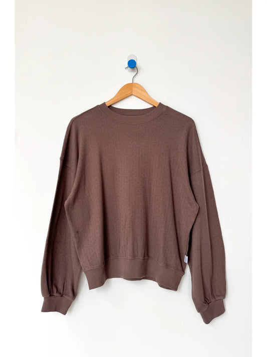 Brown sweatshirt on a wooden hanger against a white background