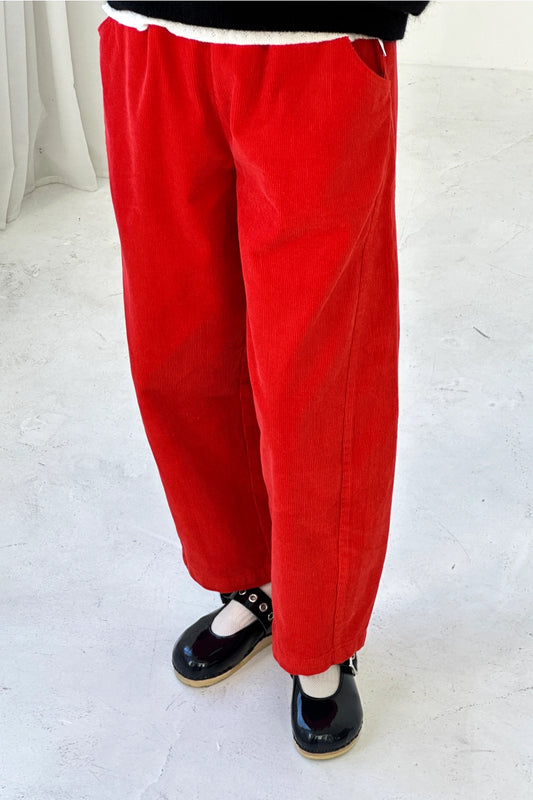 Red pants worn by a person on a white floor.