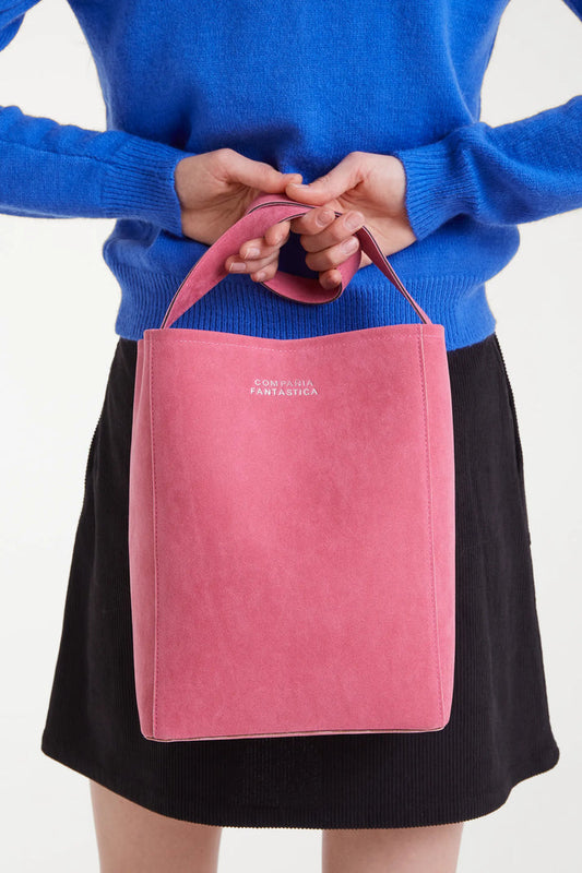 Person holding a pink tote bag with 'FANTASIA' branding against a white background