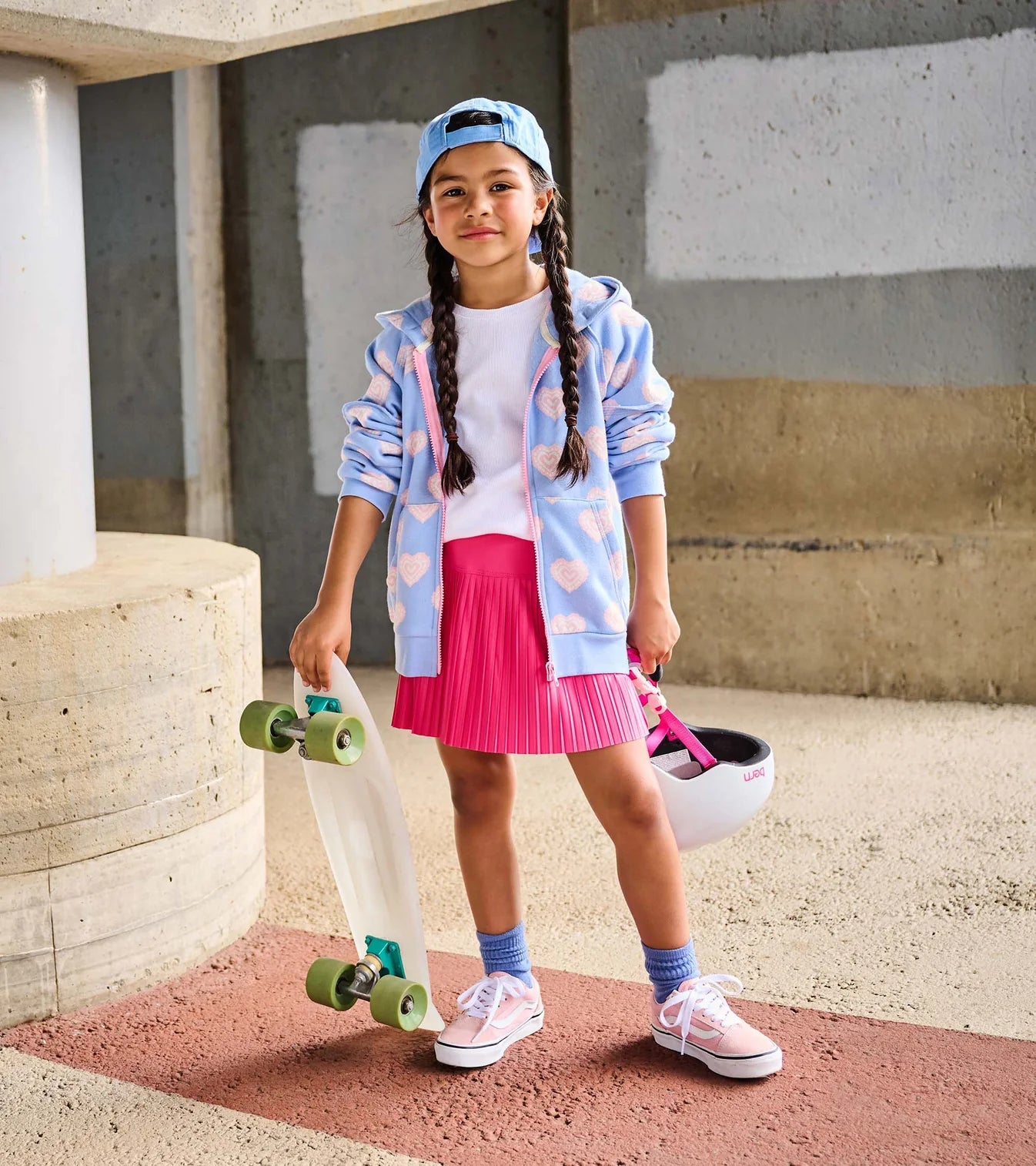 Young girl with a skateboard and helmet in an urban setting