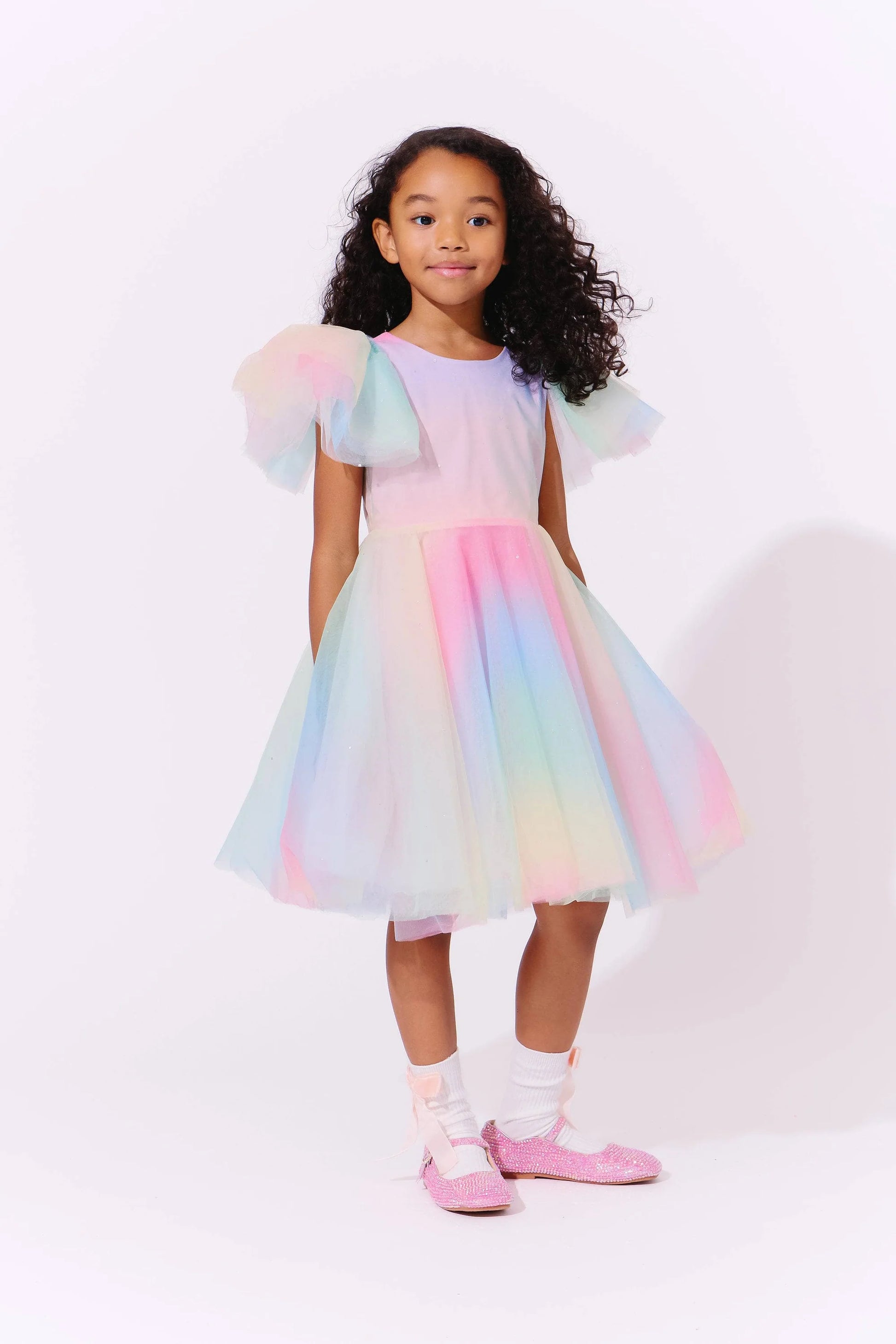 Young girl wearing a colorful dress with puffed sleeves against a white background by lola and the boys